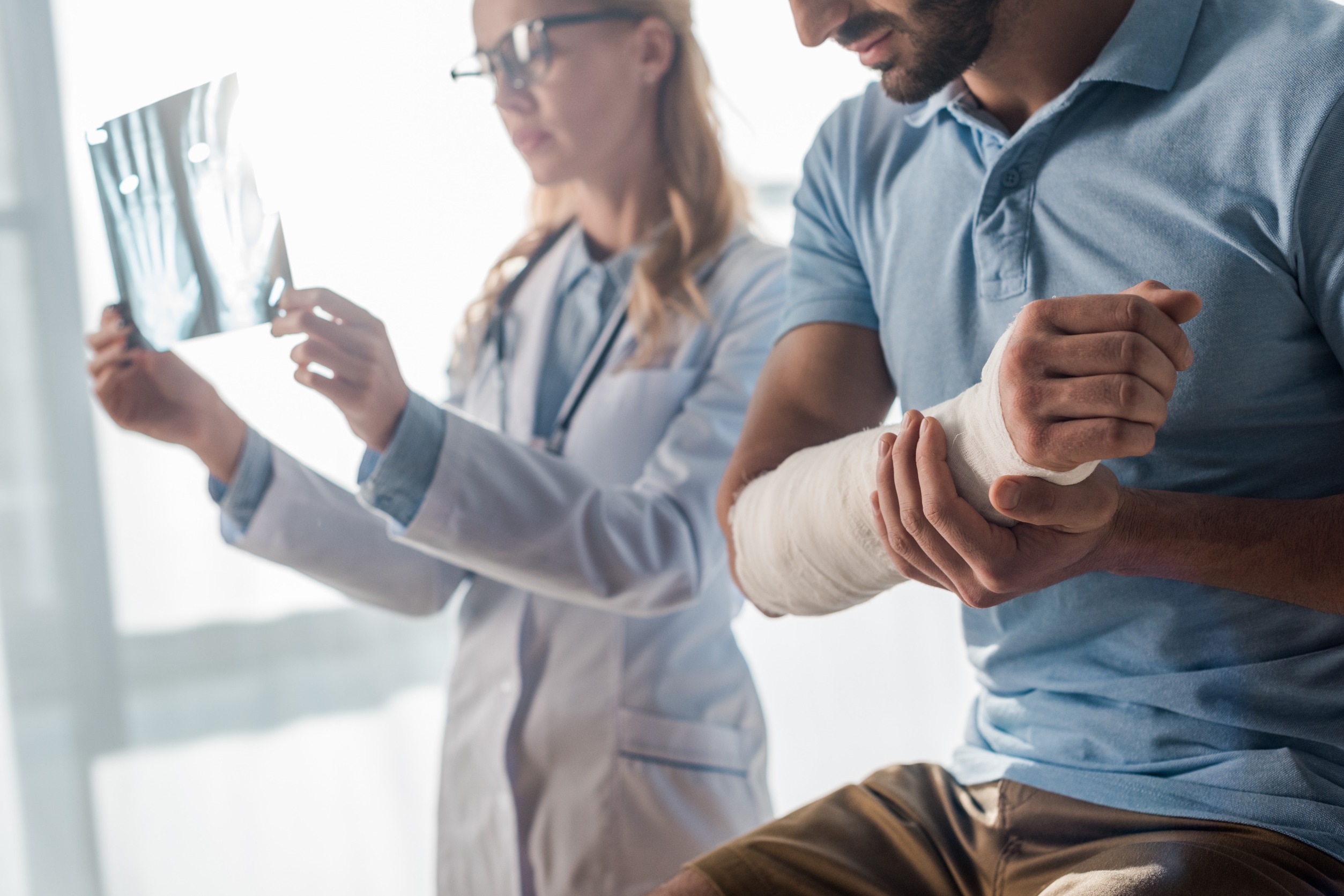 Injured Patient with Arm Cast and Doctor Holding X-Ray