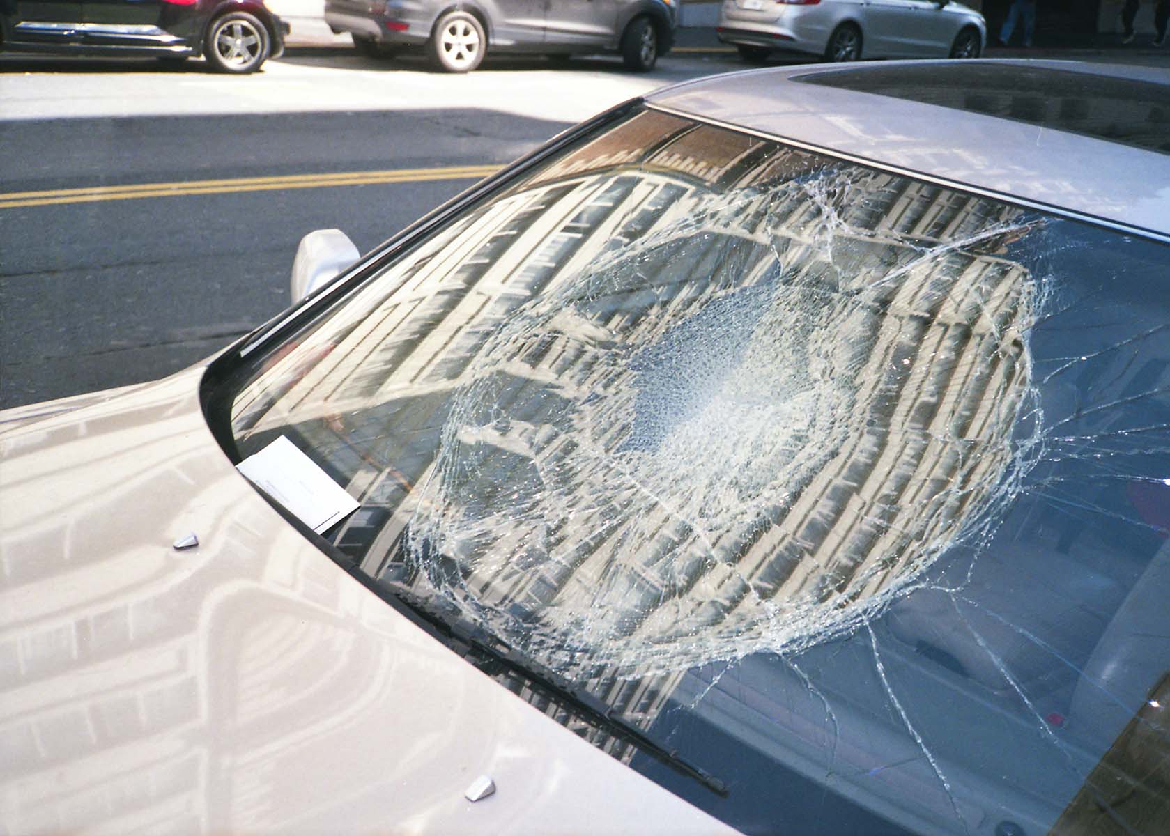 Close-up of a car’s windshield severely cracked from a high-impact collision in Midvale, Utah.