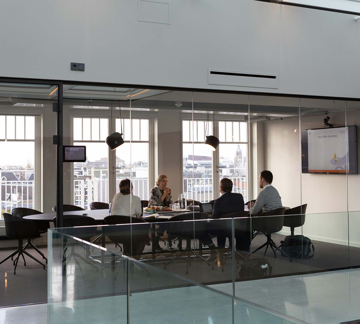 Group of people in a glass-walled conference room discussing a legal case with documents and a presentation screen.