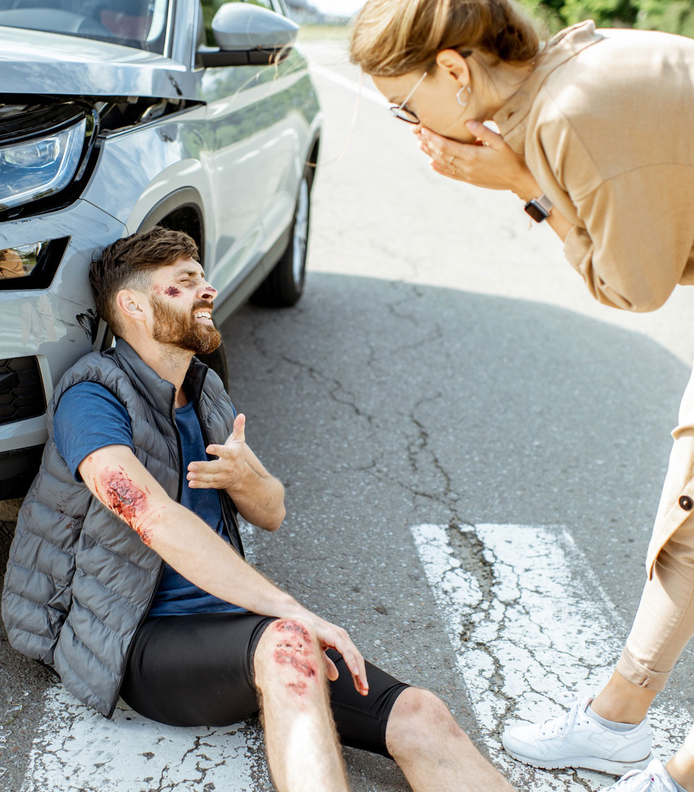 Injured pedestrian sitting on road after being hit by a car in Tacoma, with driver reacting in distress