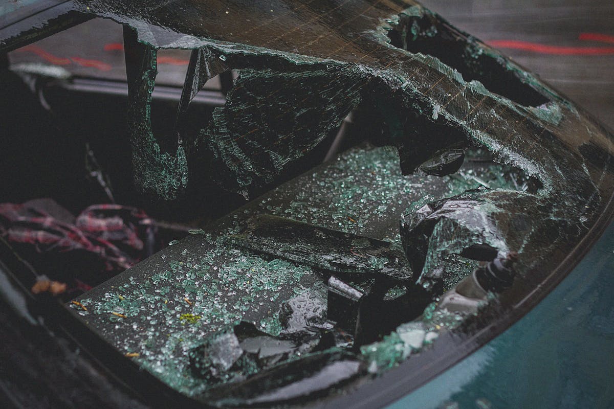 Close‑up view of a shattered car windshield with broken glass after a collision.